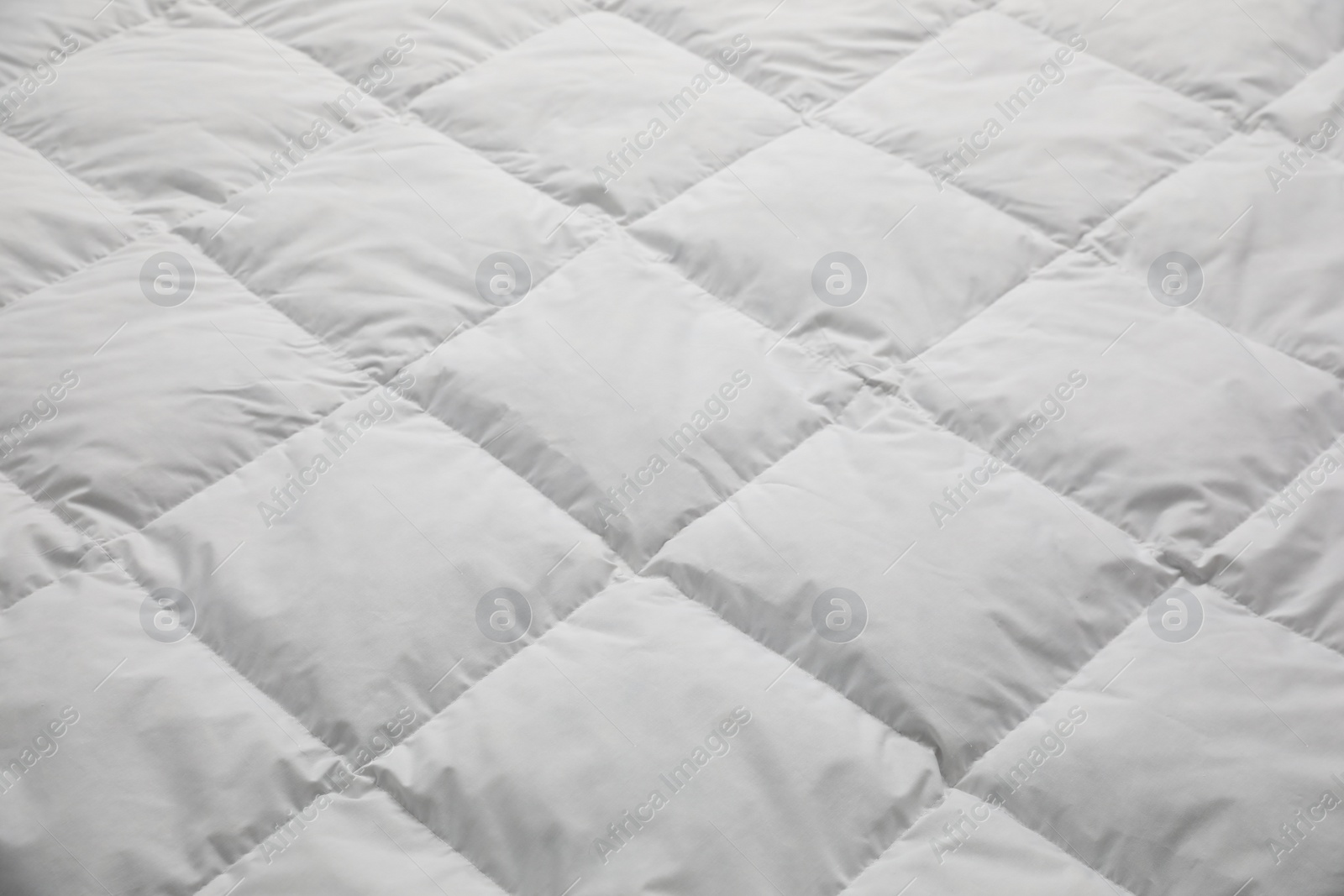 Photo of Soft quilted blanket as background, closeup view