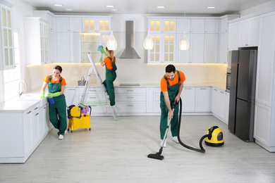 Photo of Team of professional janitors cleaning modern kitchen