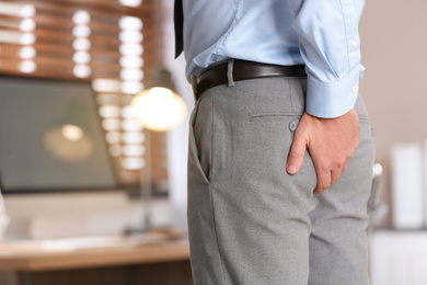 Man suffering from hemorrhoid in office, closeup