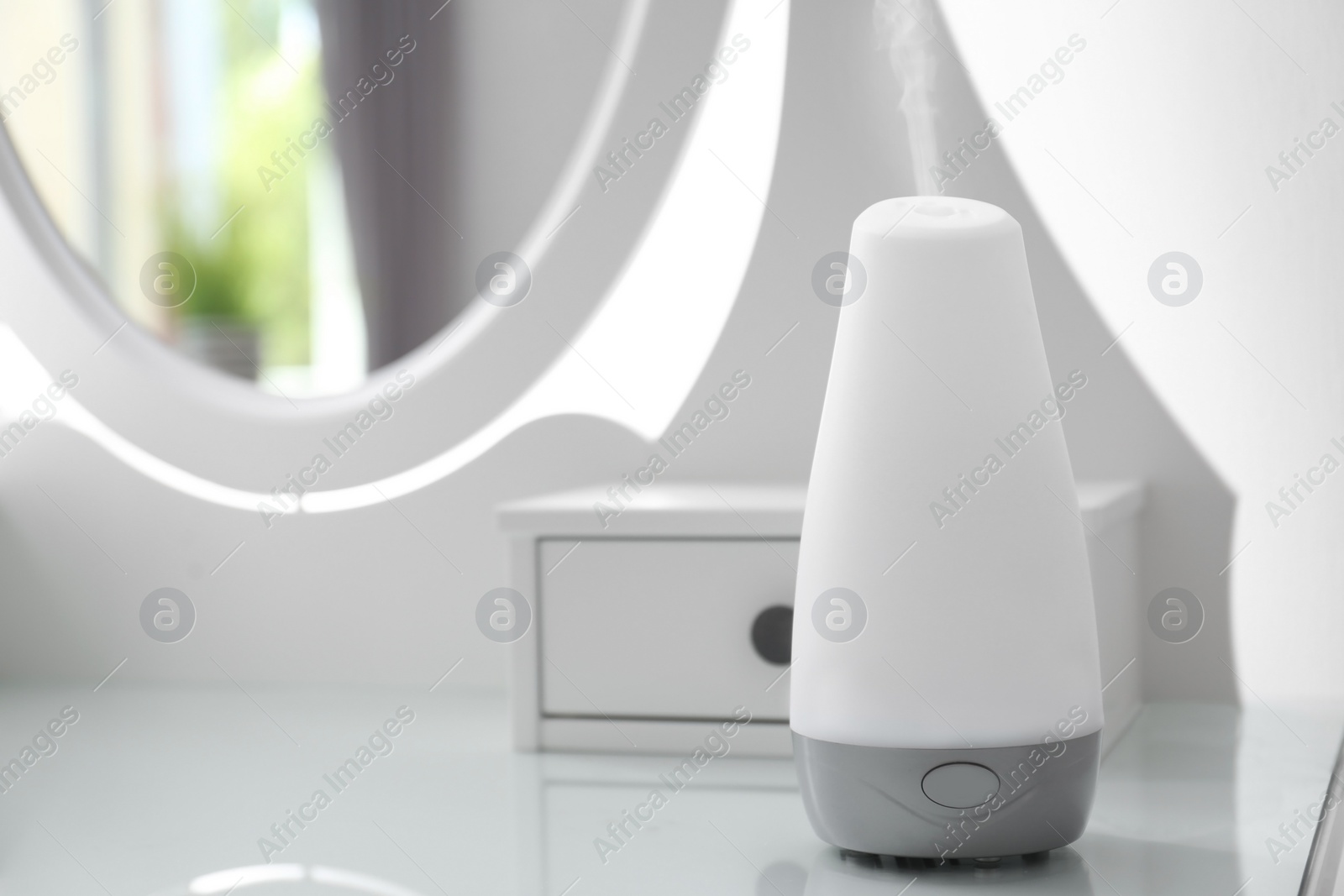 Photo of Essential oils diffuser on white table   in room. Space for text