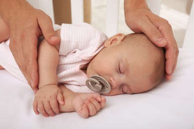 Father putting his cute baby into crib