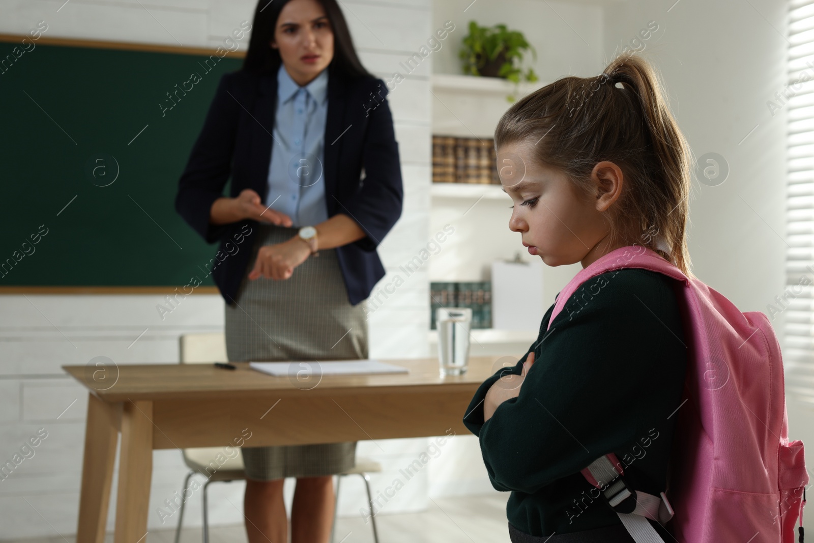 Photo of Teacher pointing on wrist watch while scolding pupil for being late in classroom