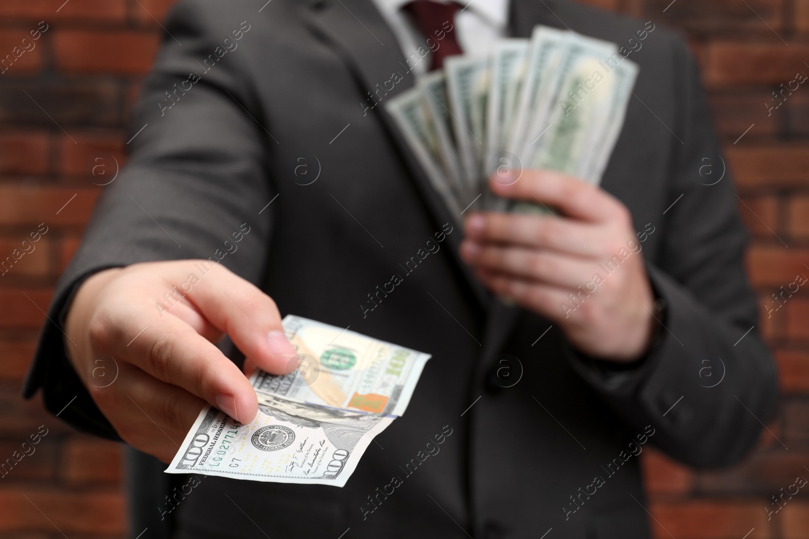 Photo of Man holding money near red brick wall, closeup. Currency exchange