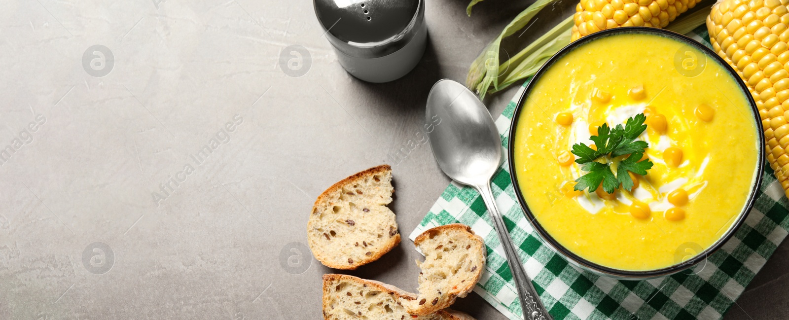 Photo of Delicious creamy corn soup served on grey table, flat lay. Space for text