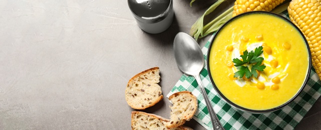 Photo of Delicious creamy corn soup served on grey table, flat lay. Space for text