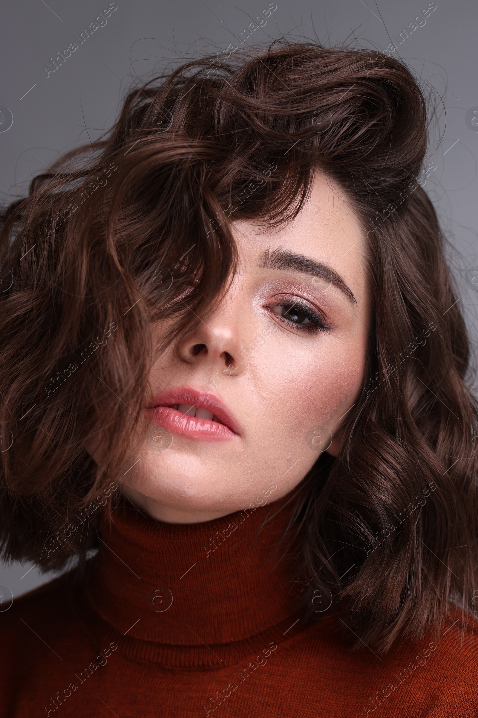 Photo of Portrait of beautiful young woman with wavy hairstyle on grey background