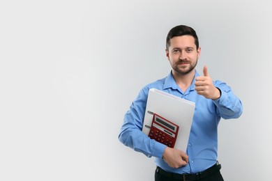 Accountant with calculator showing thumb up on light grey background. Space for text