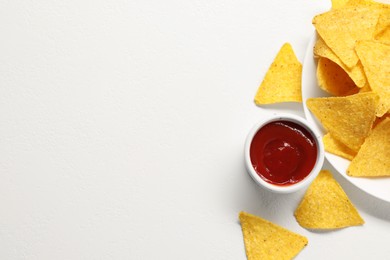 Tasty ketchup and tortilla chips on white table, flat lay. Space for text