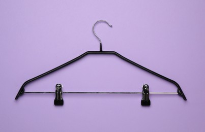 Empty clothes hanger on violet background, top view