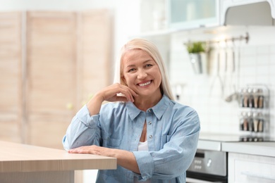 Photo of Portrait of happy mature woman at table indoors