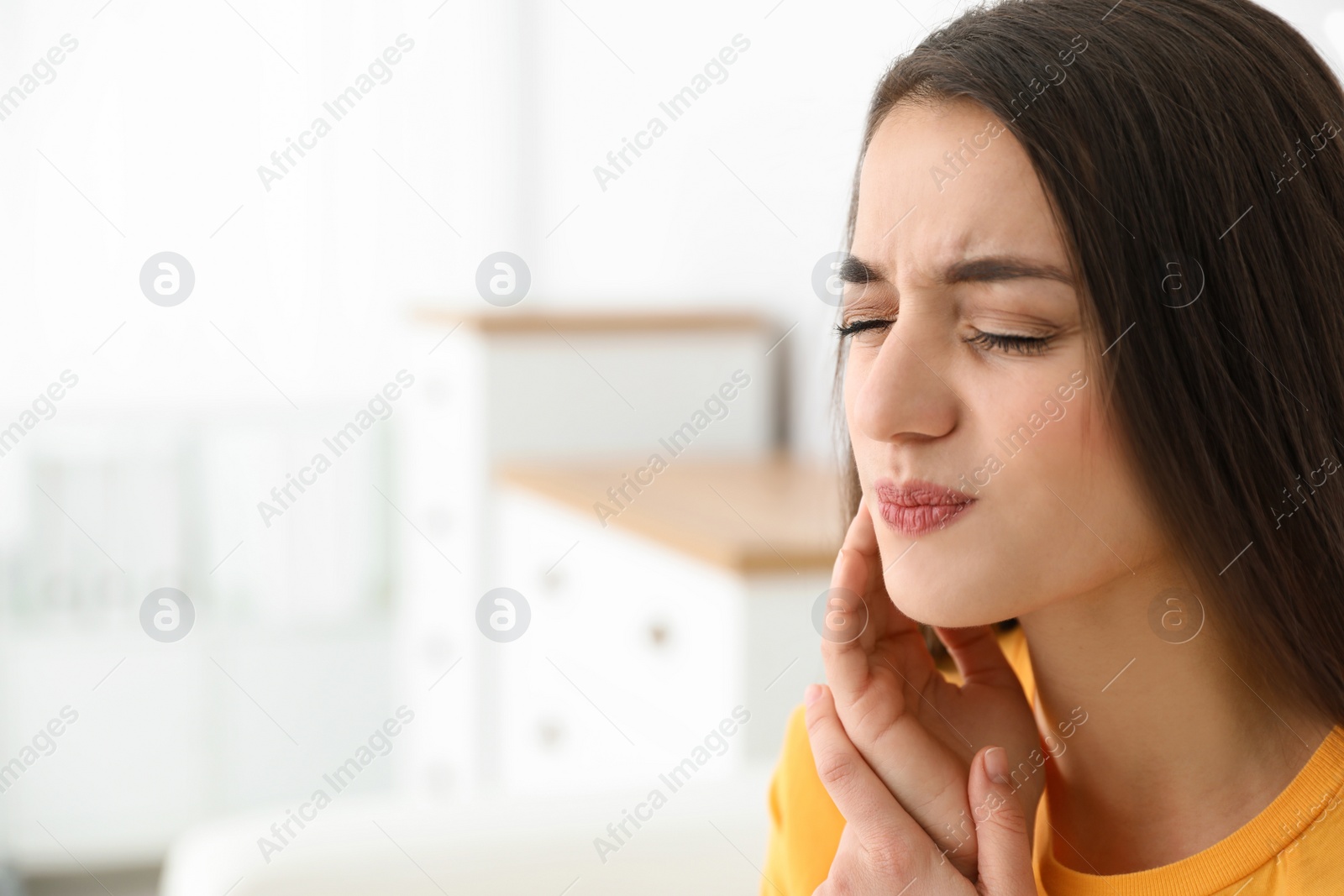 Photo of Young woman suffering from strong tooth pain at home, space for text