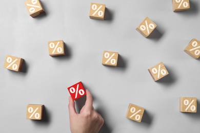 Image of Best mortgage interest rate. Woman taking red cube with percent sign among wooden ones on light background, top view