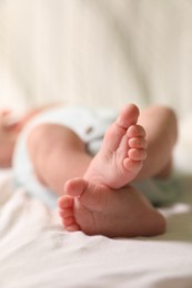 Cute newborn baby lying on bed, closeup of legs