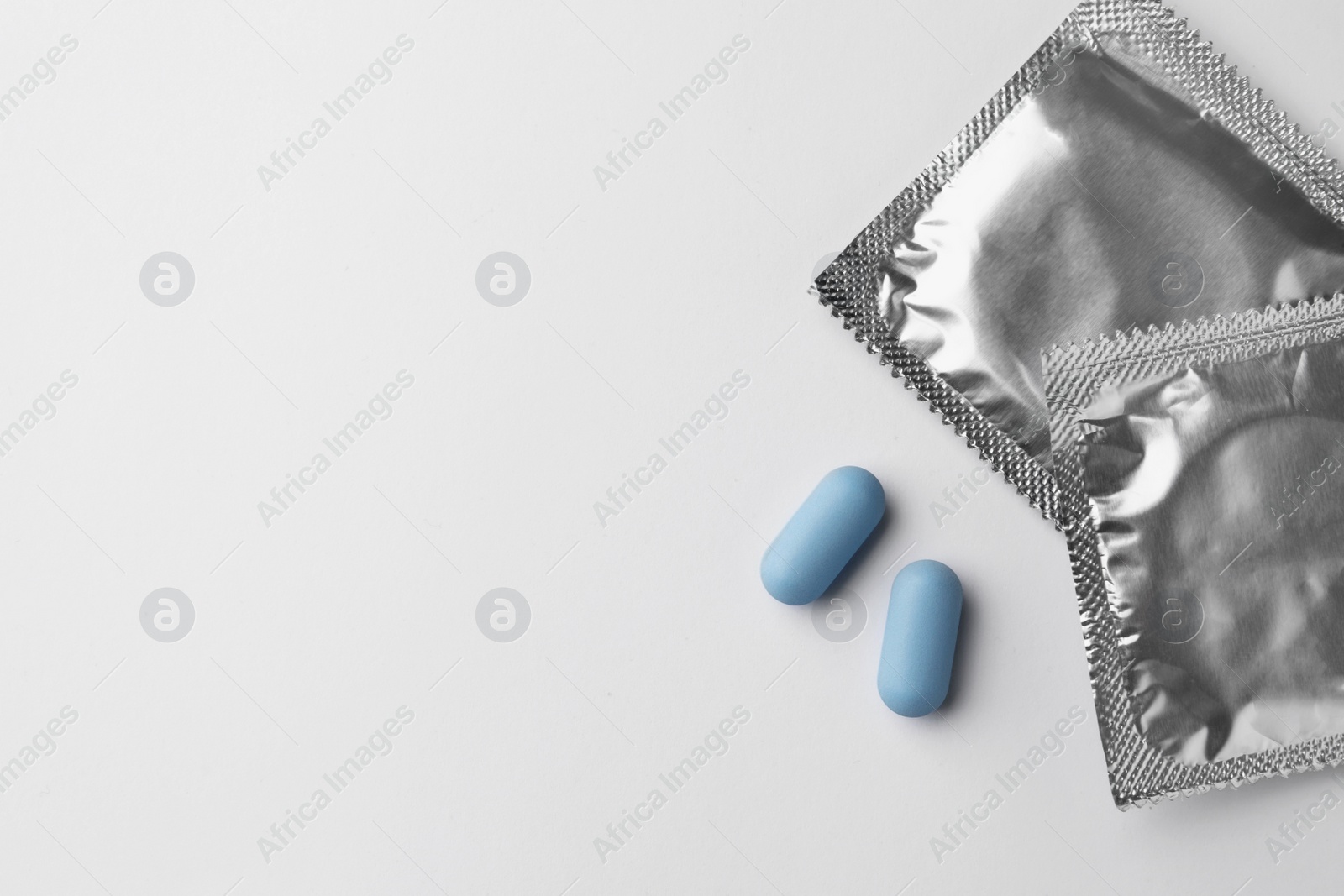 Photo of Pills and condoms on white background, flat lay with space for text. Potency problem