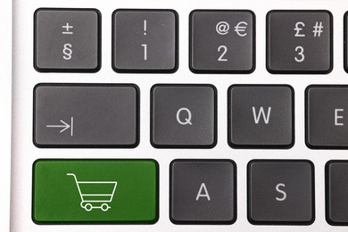 Image of Internet store. Green button with shopping cart on computer keyboard, top view