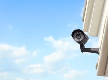 Modern CCTV security camera on building outdoors. Space for text