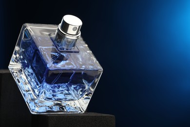 Luxury men`s perfume in bottle against dark blue background, space for text