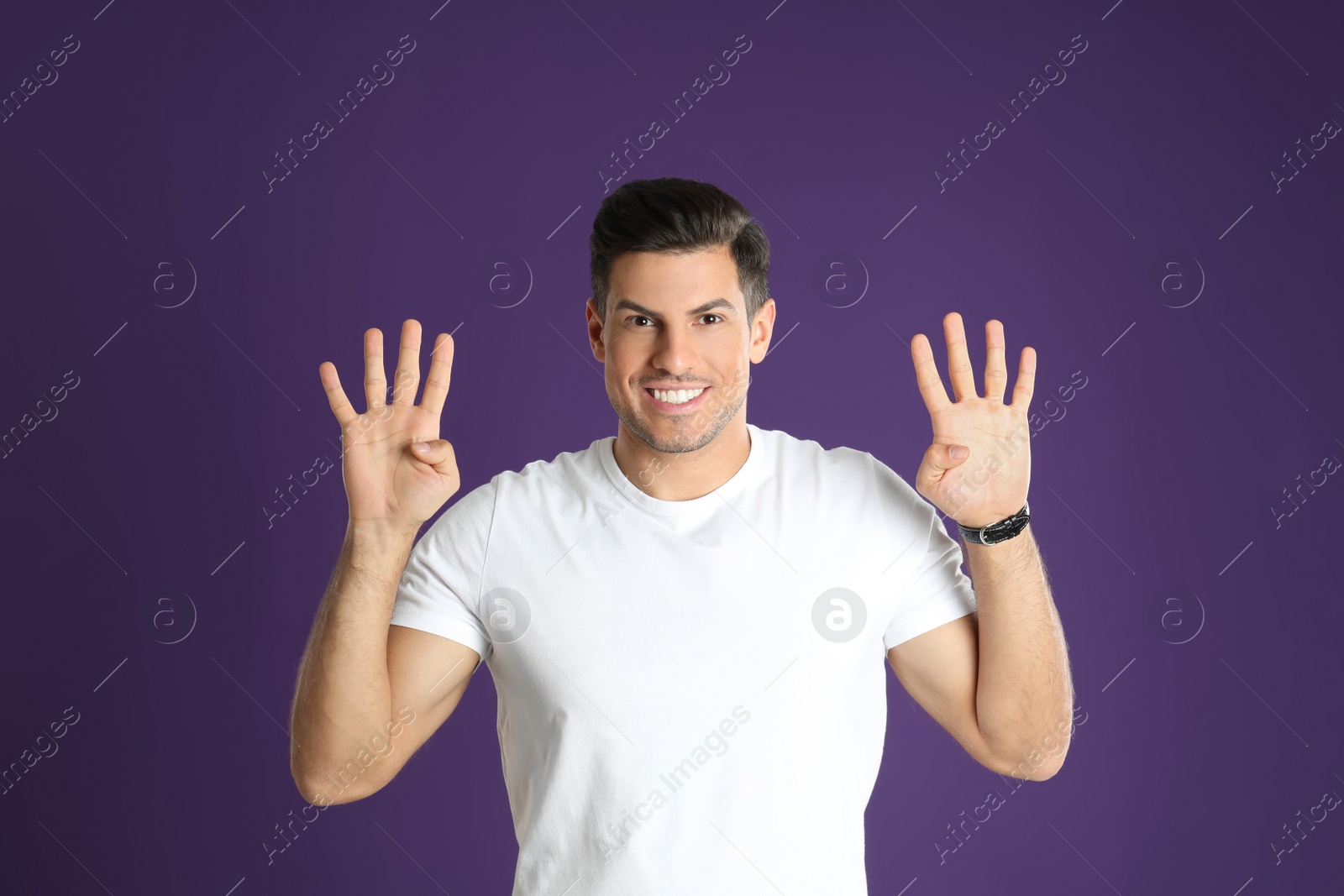 Photo of Man showing number eight with his hands on purple background