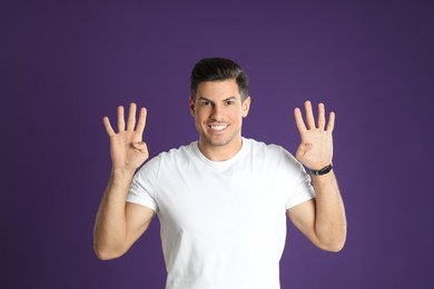 Man showing number eight with his hands on purple background