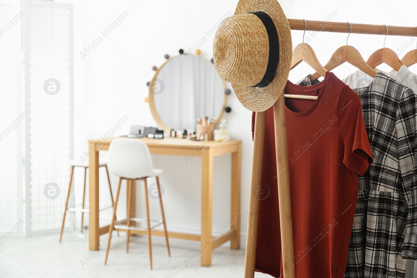 Photo of Hangers with stylish clothes and hat on rack in makeup room. Space for text