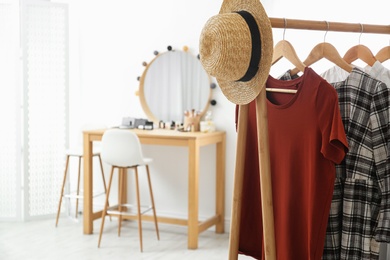 Photo of Hangers with stylish clothes and hat on rack in makeup room. Space for text