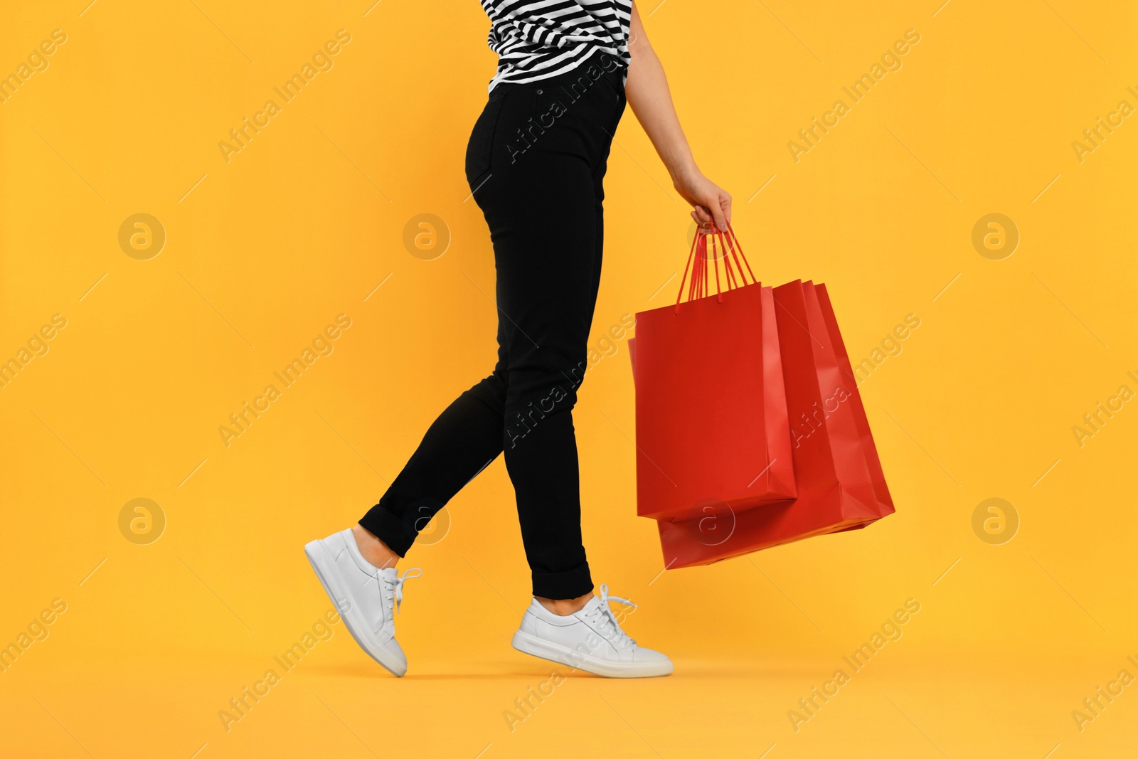 Photo of Woman with shopping bags on yellow background, closeup