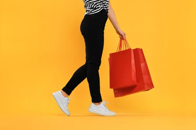 Woman with shopping bags on yellow background, closeup