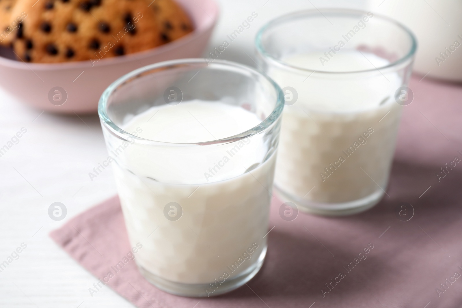 Photo of Glasses of delicious milk on light table