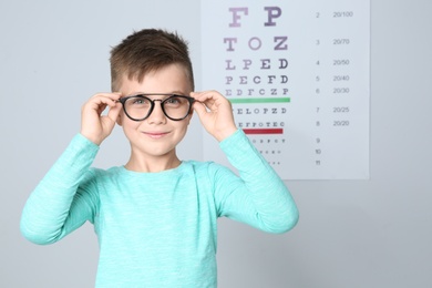 Photo of Little boy with glasses visiting children's doctor in clinic, space for text. Eye examination