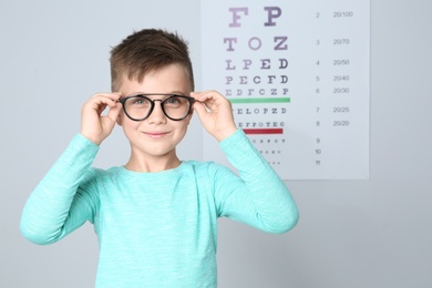 Little boy with glasses visiting children's doctor in clinic, space for text. Eye examination