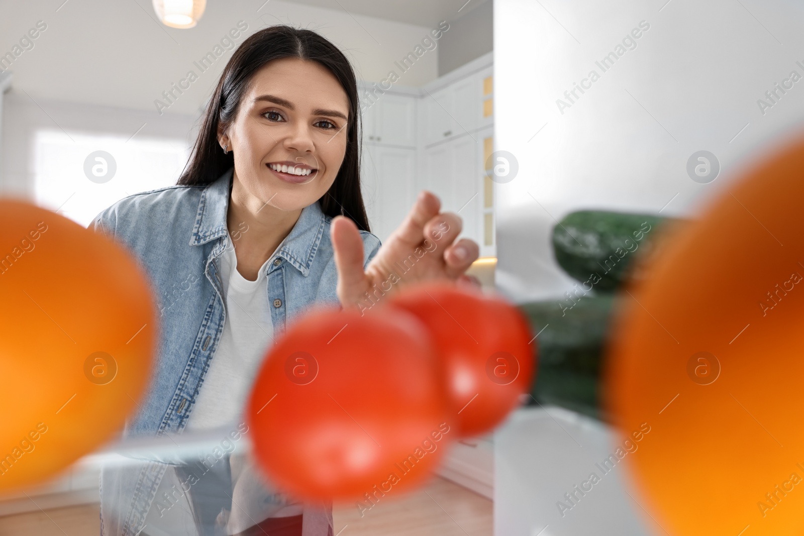 Photo of Thoughtful woman near refrigerator in kitchen, view from inside