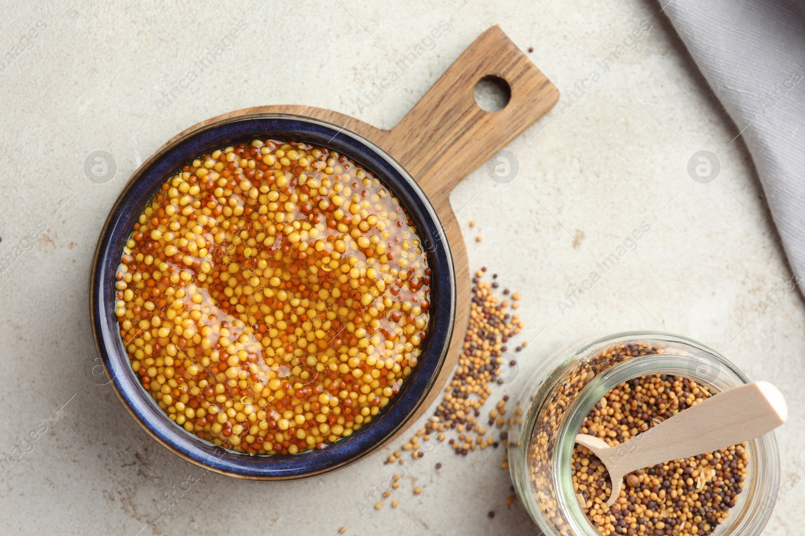 Photo of Whole grain mustard and dry seeds on white table, flat lay