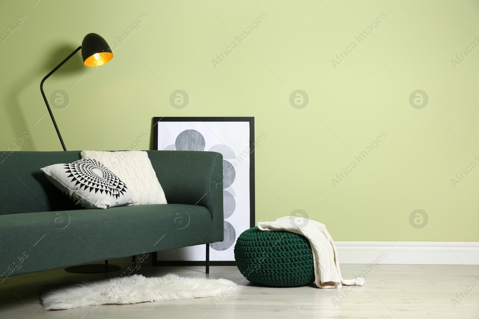Photo of Stylish living room interior with comfortable knitted pouf and sofa near light green wall, space for text