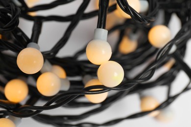 Photo of Beautiful Christmas lights on white background, closeup