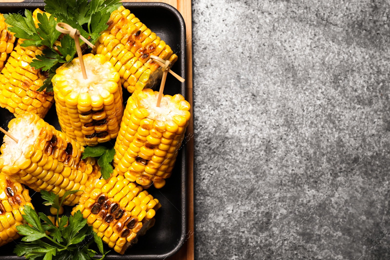 Photo of Tasty grilled corn on grey table, top view. Space for text