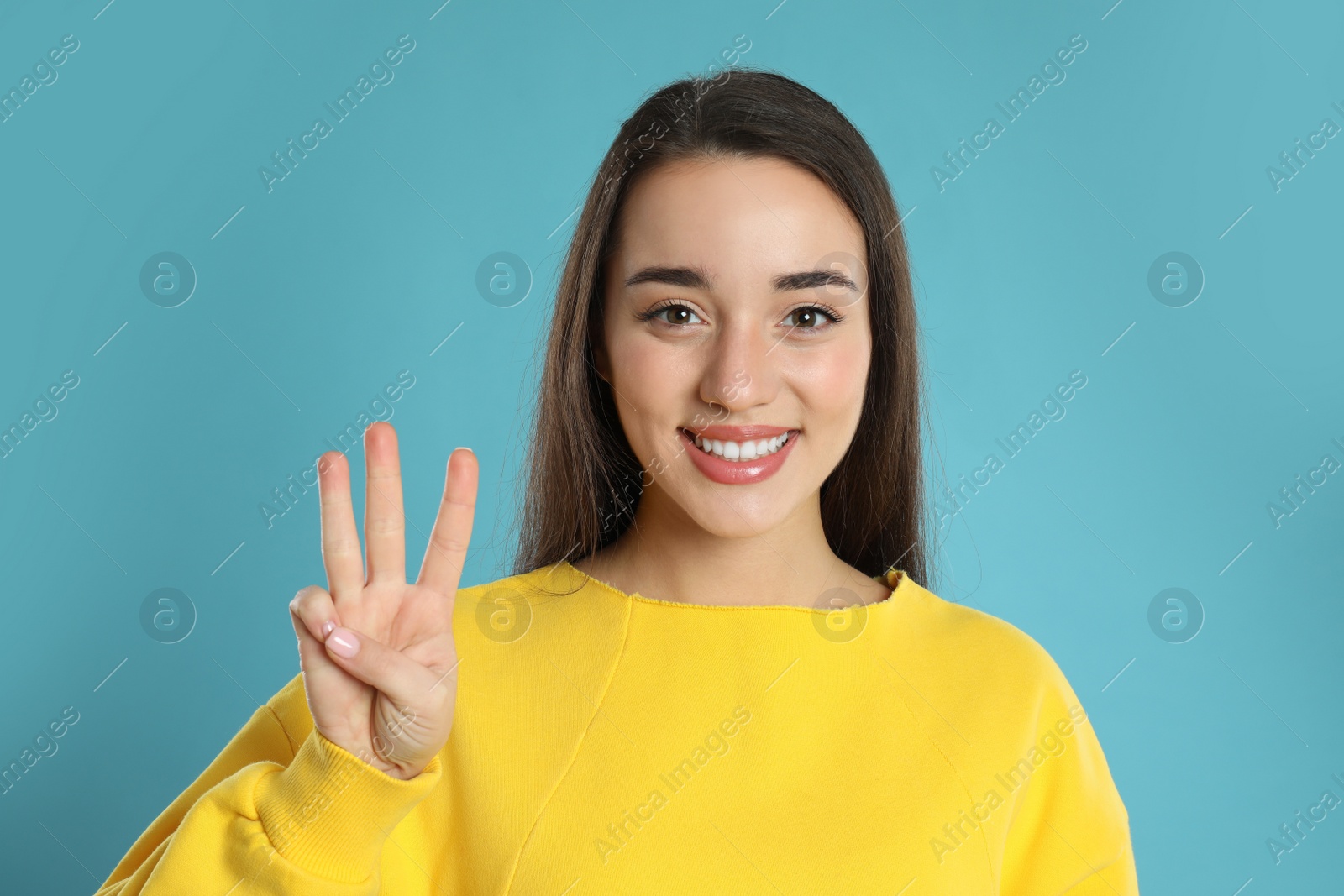 Photo of Woman showing number three with her hand on light blue background