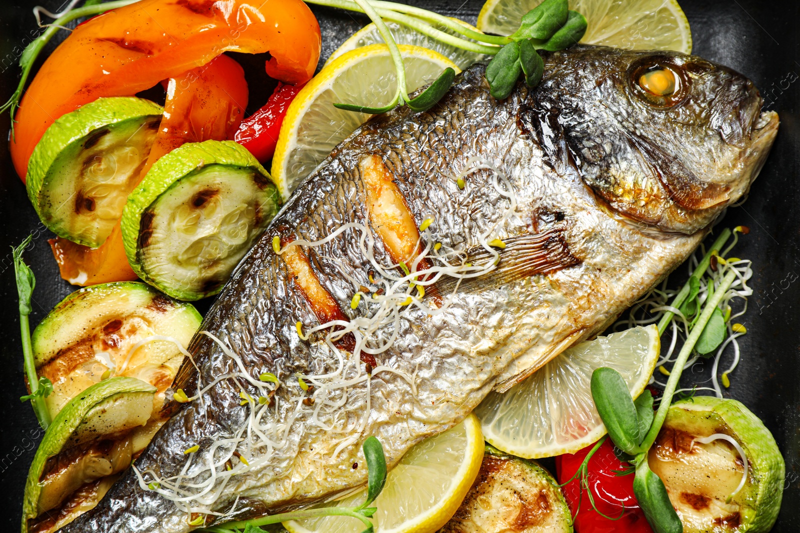 Photo of Delicious roasted fish and vegetables in pan, top view