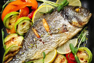 Photo of Delicious roasted fish and vegetables in pan, top view