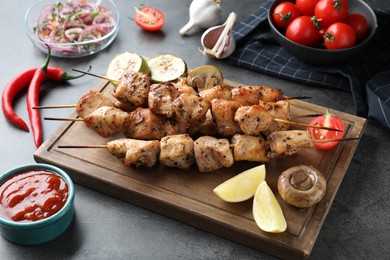 Photo of Delicious shish kebabs with vegetables served on grey table