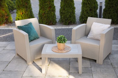 Photo of Beautiful rattan garden furniture, soft pillows and houseplant outdoors