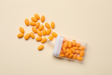 Photo of Tasty orange dragee candies and container on yellow background, flat lay