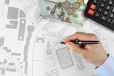 Photo of Cartographer with calculator and money drawing cadastral map, closeup