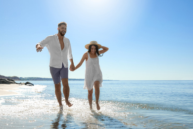 Photo of Happy young couple running on beach near sea. Honeymoon trip