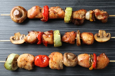 Delicious shish kebabs with vegetables on black table, top view