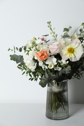 Photo of Bouquet of beautiful flowers in vase on white table