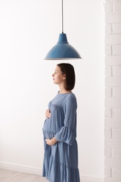 Beautiful pregnant woman standing in light room