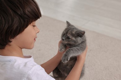 Cute little boy with kitten at home. Childhood pet