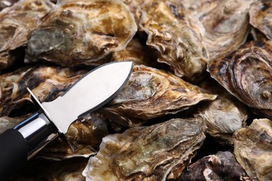 Photo of Knife on pile of fresh oysters, closeup