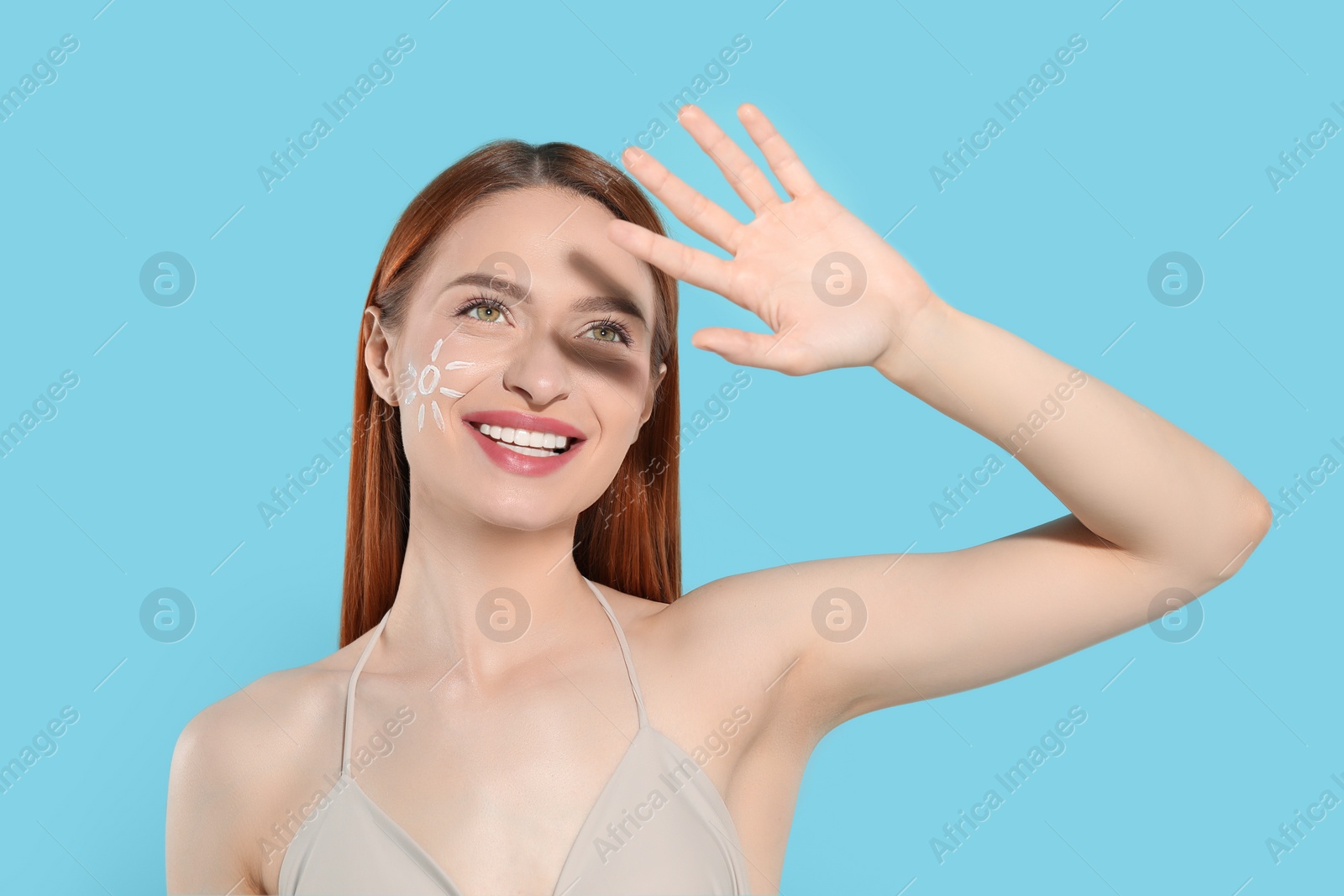 Photo of Beautiful young woman shading herself with hand from sunlight on light blue background