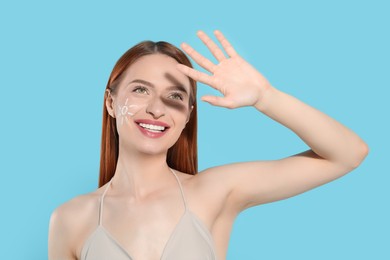Beautiful young woman shading herself with hand from sunlight on light blue background